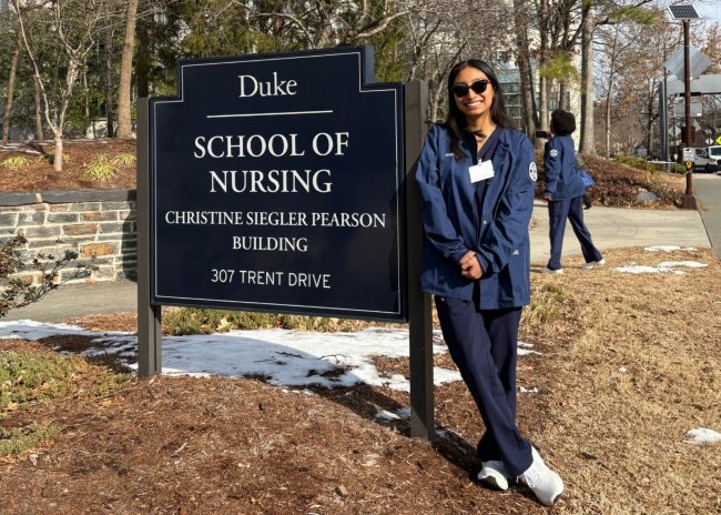 Andrea Ramirez Martinez leaning against the Duke School of Nursing Pearson Building sign