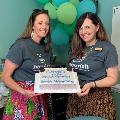 two women holding cake at grand opening